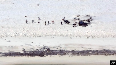 Para nelayan dari Indonesia berdiri di sebuah pantai di Pulau Bedwell, 313 kilometer sebelah barat Broome, Australia, Senin, 17 April 2023. (Otoritas Keselamatan Maritim Australia via AP)