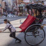 PEnarik becak perempuan saat mengantar dua orang penumpang perempuan di Asakusa, Tokyo.