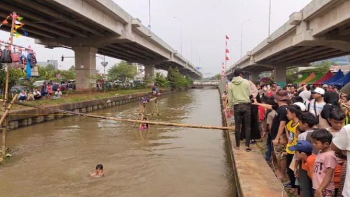 Suasana riuh penonton menyaksikan peserta lomba titian bambu tercebur di aliran Kalimalang dalam lomba diadakan warga RW 04, Cipinang Melayu, Makasar, Jakarta Timur, pada Sabtu (24/8/2024) siang-sore. Foto: Joesvicar Iqbal/ipol.id